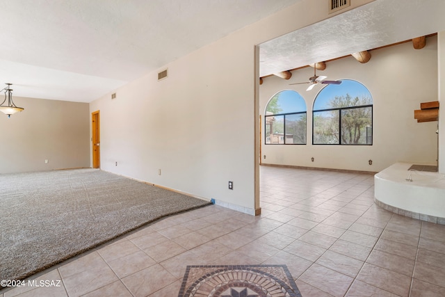 tiled spare room with beamed ceiling and ceiling fan