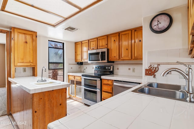 kitchen with backsplash, tile countertops, sink, and stainless steel appliances