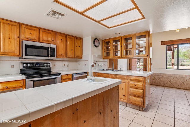 kitchen featuring tasteful backsplash, tile countertops, light tile patterned floors, and stainless steel appliances