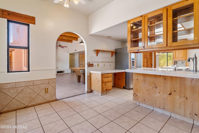 kitchen featuring stainless steel fridge with ice dispenser, tile countertops, ceiling fan, and light tile patterned floors