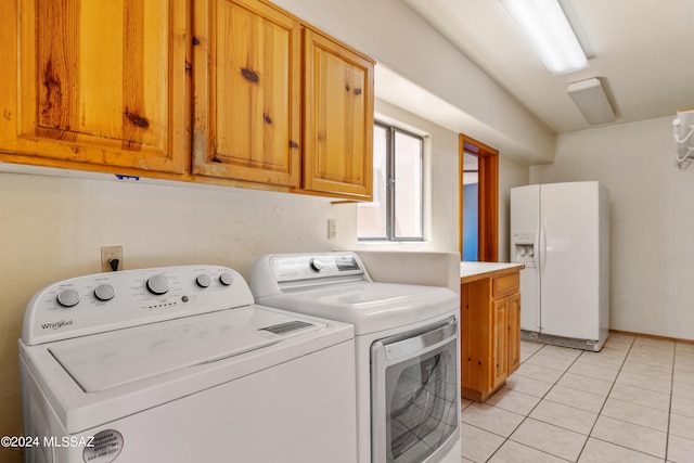 clothes washing area featuring cabinets, light tile patterned floors, and washer and dryer