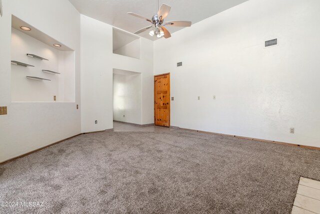 unfurnished room with a high ceiling, carpet floors, and ceiling fan