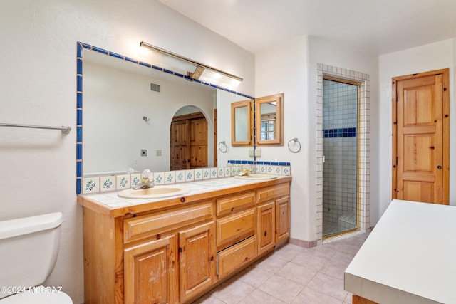 bathroom featuring tile patterned flooring, vanity, toilet, and a shower with door