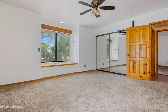 unfurnished bedroom featuring ceiling fan, light colored carpet, and a closet