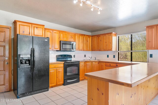 kitchen with kitchen peninsula, sink, tasteful backsplash, and black appliances