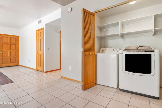 laundry room with independent washer and dryer and light tile patterned floors