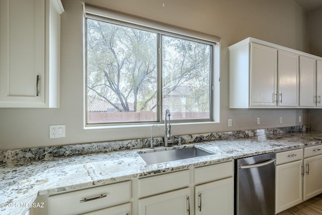 kitchen featuring white cabinets, light stone countertops, and sink