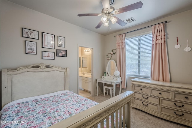 bedroom with ceiling fan, light colored carpet, and connected bathroom