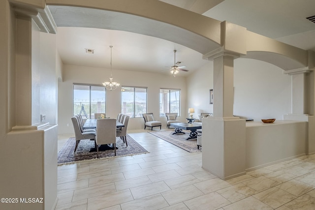 dining area with ceiling fan with notable chandelier, lofted ceiling, and decorative columns