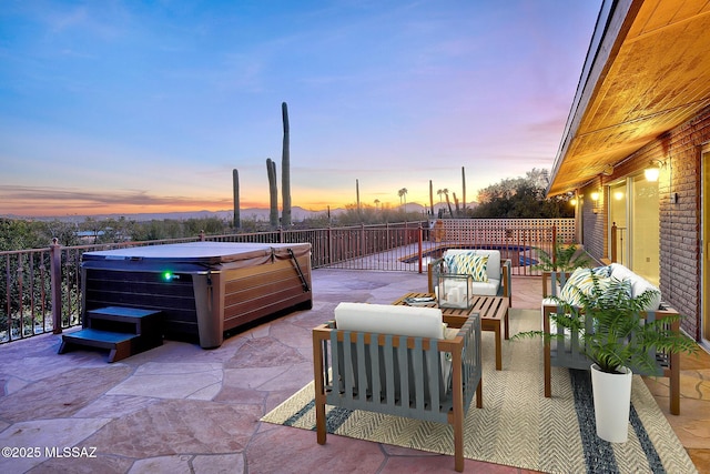 patio terrace at dusk featuring outdoor lounge area and a hot tub