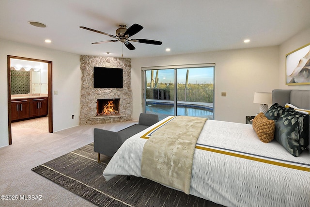 carpeted bedroom with access to exterior, ceiling fan, a fireplace, and ensuite bath