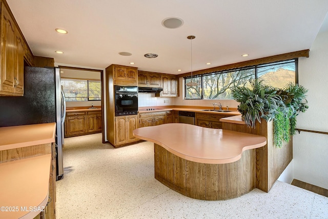 kitchen featuring sink, tasteful backsplash, kitchen peninsula, decorative light fixtures, and appliances with stainless steel finishes