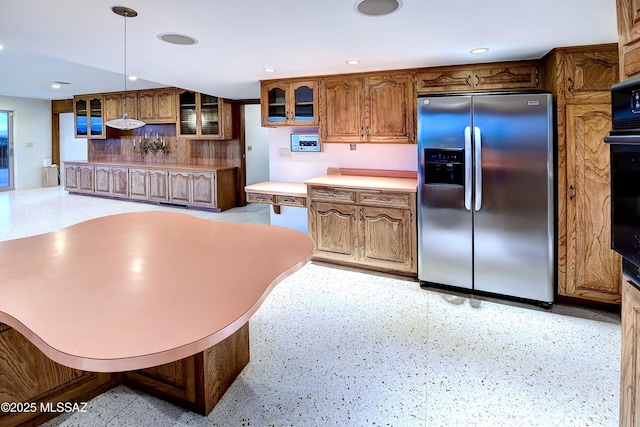 kitchen featuring decorative light fixtures, stainless steel fridge, backsplash, and black oven