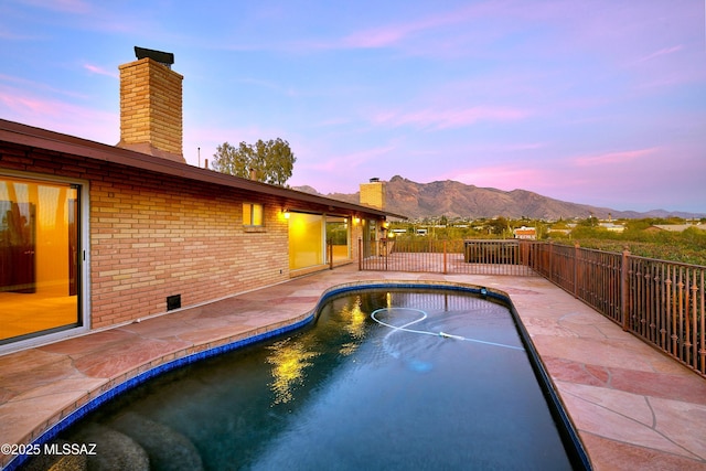 pool at dusk with a mountain view and a patio