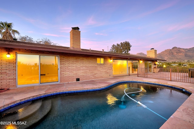 pool at dusk with a mountain view and a patio area