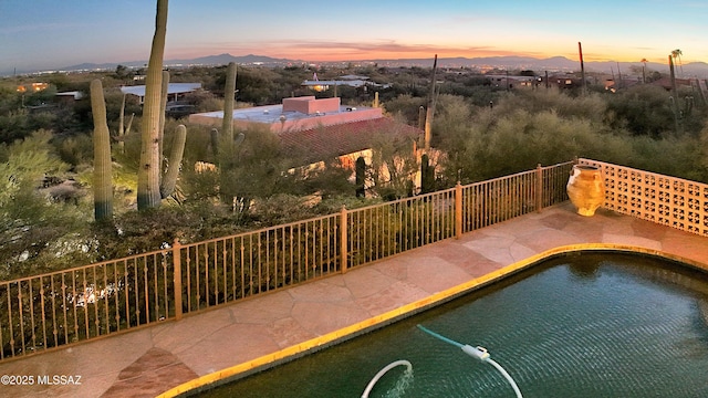 pool at dusk featuring a mountain view