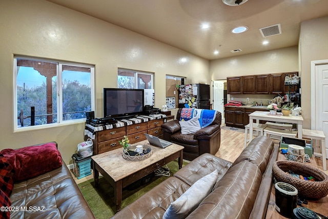 living room with light hardwood / wood-style flooring and a towering ceiling