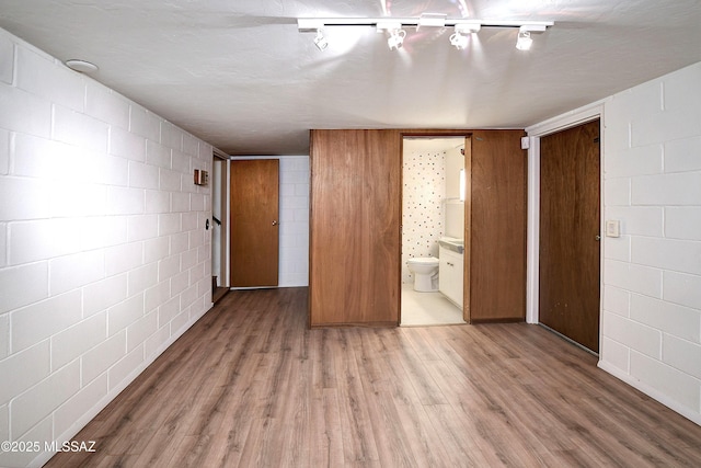 unfurnished bedroom featuring ensuite bath, light hardwood / wood-style flooring, and a closet