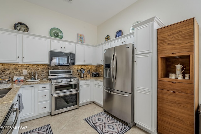 kitchen with tasteful backsplash, light stone counters, white cabinets, and appliances with stainless steel finishes