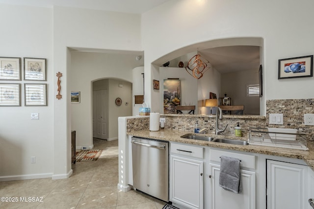 kitchen featuring light stone countertops, white cabinets, tasteful backsplash, sink, and dishwasher