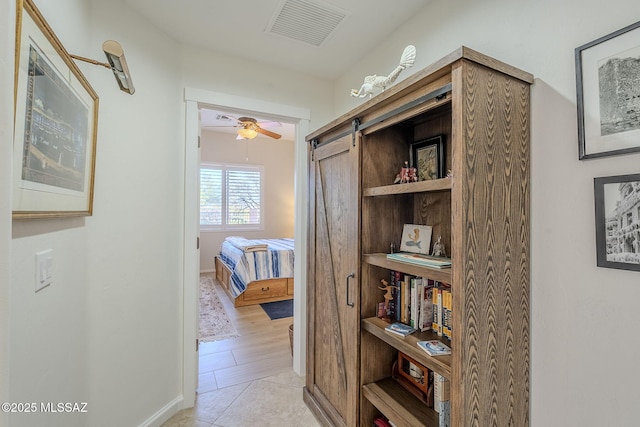 corridor with a barn door and light tile patterned flooring