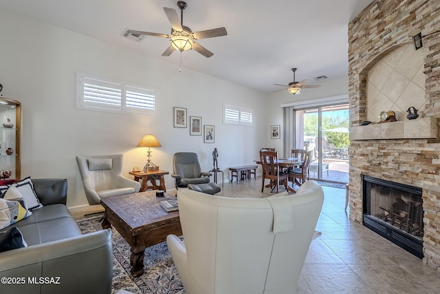 living room featuring a stone fireplace and ceiling fan