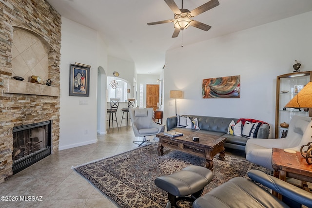 living room featuring a fireplace, ceiling fan, and light tile patterned flooring