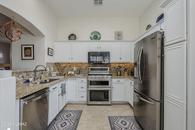 kitchen with sink, light stone countertops, appliances with stainless steel finishes, tasteful backsplash, and white cabinetry