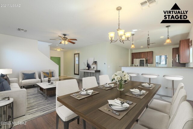 dining area featuring ceiling fan with notable chandelier and dark hardwood / wood-style floors