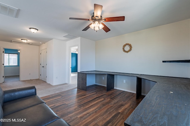 unfurnished office with built in desk, visible vents, ceiling fan, wood finished floors, and baseboards