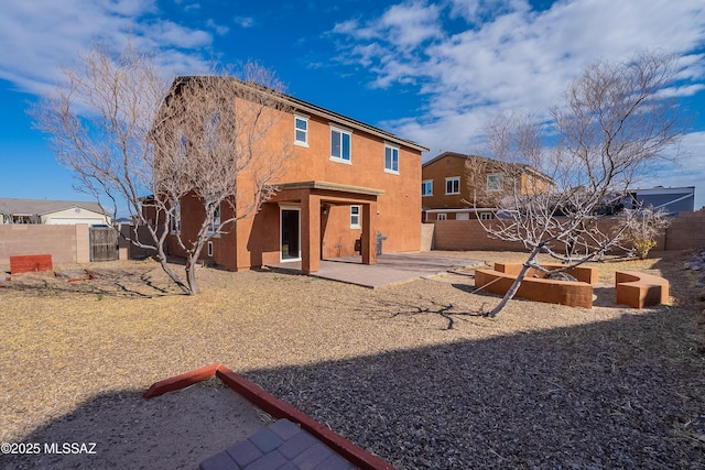 rear view of house featuring a patio, a fenced backyard, and stucco siding