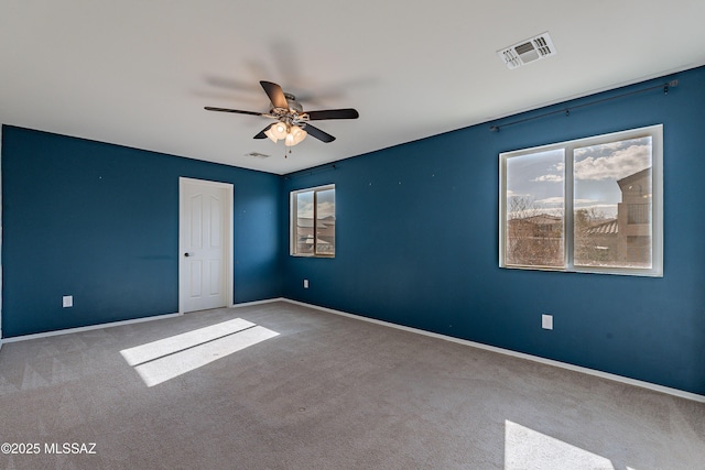 carpeted empty room featuring ceiling fan, visible vents, and baseboards