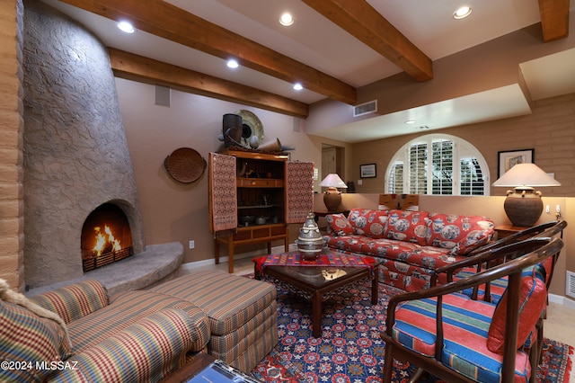 living room featuring beam ceiling and a stone fireplace