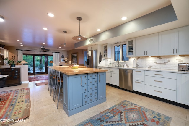 kitchen featuring a center island, a kitchen breakfast bar, decorative light fixtures, white cabinets, and appliances with stainless steel finishes