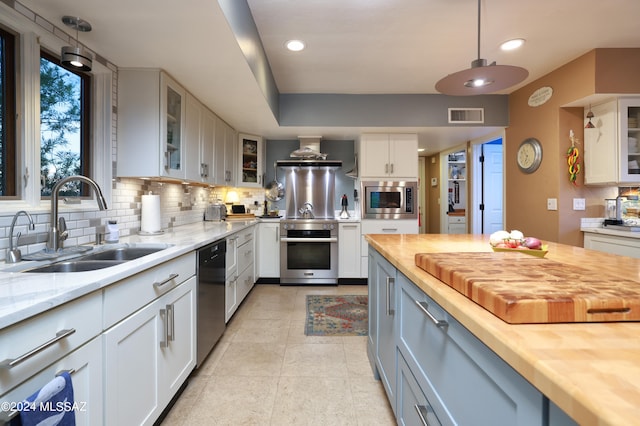 kitchen with wooden counters, sink, dishwasher, white cabinets, and stainless steel microwave