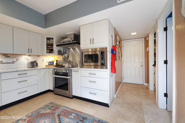 kitchen with white cabinets, light stone countertops, stainless steel appliances, and tasteful backsplash