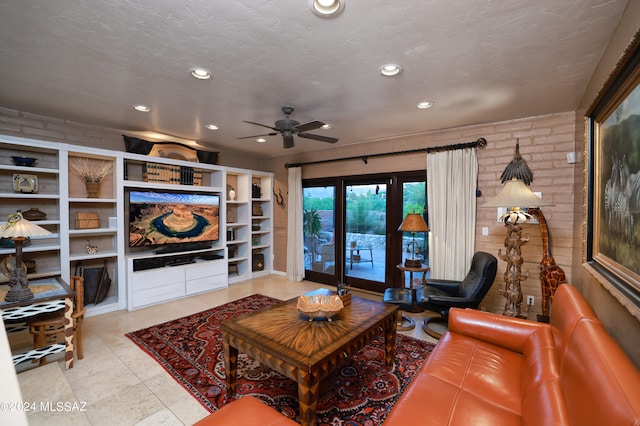 living room featuring ceiling fan, a textured ceiling, brick wall, and french doors