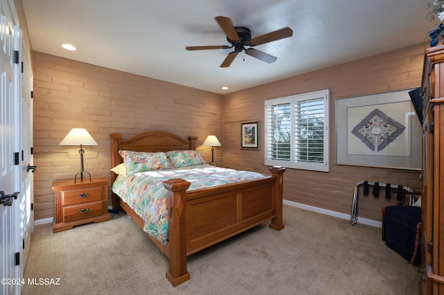 bedroom with ceiling fan, light colored carpet, and brick wall