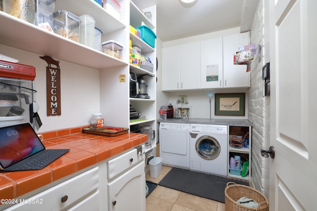 laundry room featuring cabinets, light tile patterned floors, and separate washer and dryer