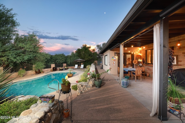 pool at dusk with a patio area