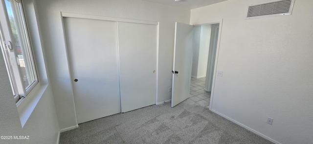 unfurnished bedroom with light carpet and a closet