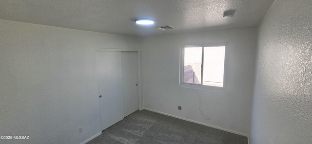 unfurnished room featuring dark carpet and a textured ceiling