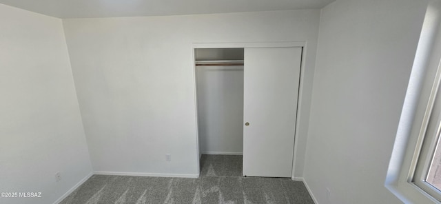 unfurnished bedroom with dark colored carpet and a closet