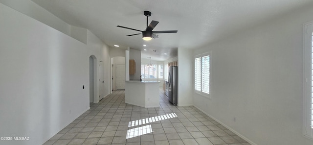 unfurnished living room featuring ceiling fan with notable chandelier, light tile patterned floors, and lofted ceiling