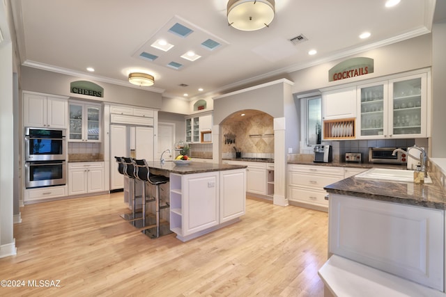 kitchen with a kitchen breakfast bar, white cabinetry, a kitchen island with sink, and tasteful backsplash