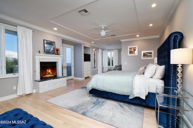 bedroom featuring ceiling fan, crown molding, wood-type flooring, and a fireplace