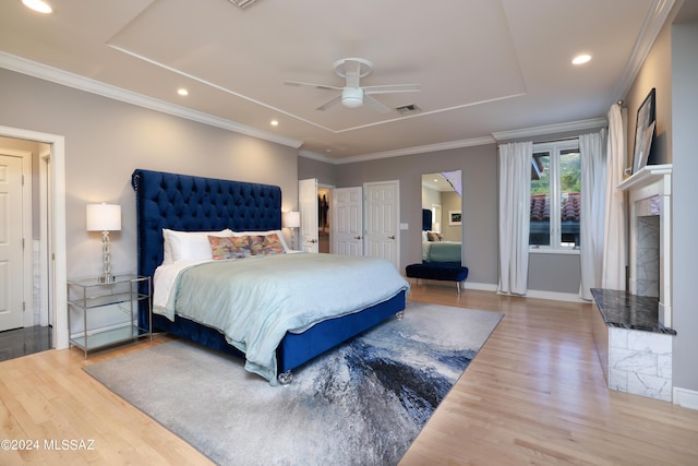 bedroom featuring a raised ceiling, ceiling fan, crown molding, and wood-type flooring