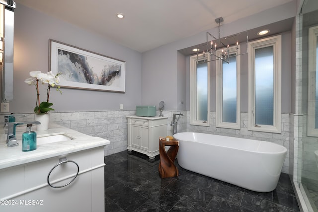 bathroom featuring vanity, tile walls, independent shower and bath, and a chandelier