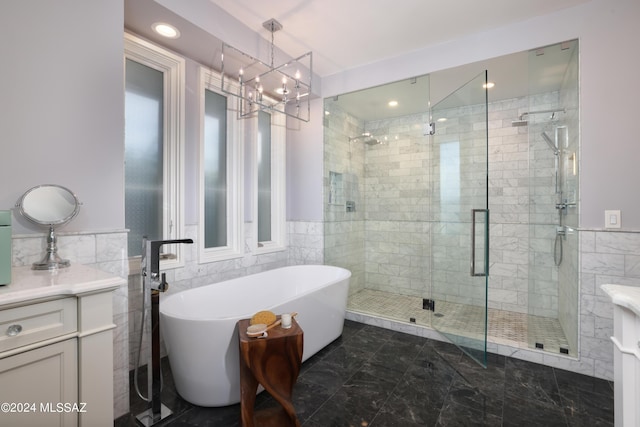 bathroom featuring vanity, tile walls, plus walk in shower, and a chandelier