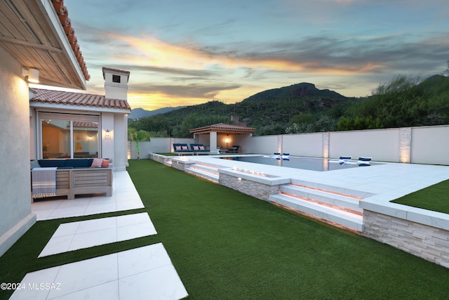 yard at dusk featuring a mountain view, an outdoor living space, and a patio